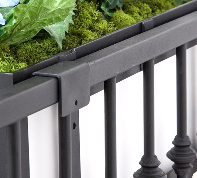 Black railing with decorative plants in a planter box.