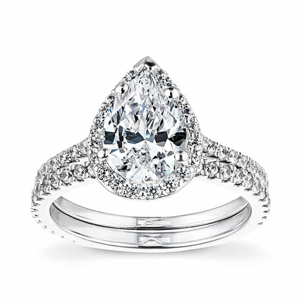 White gold wedding ring set featuring a pear cut diamond halo with diamond accenting down the band and a diamond accented wedding band