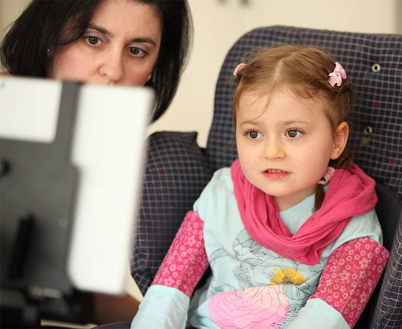 Child with her mother using a Tobii Dynavox AAC device 