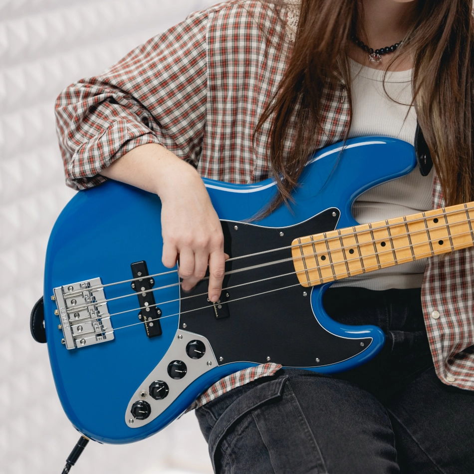 Person playing a blue Fender Jazz Bass guitar.