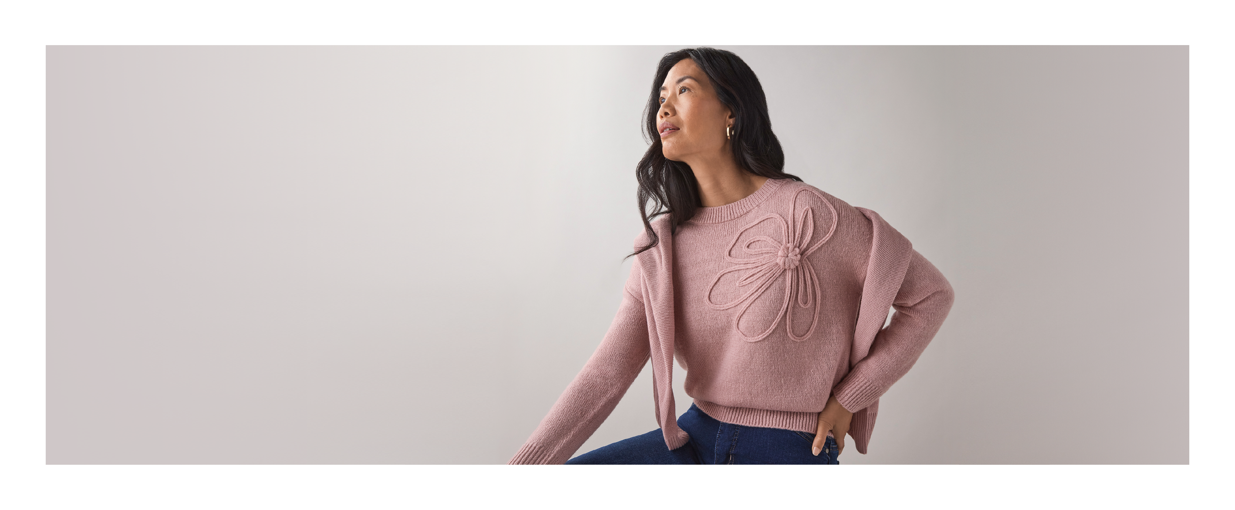 Woman in a pink sweater posing against a neutral background.