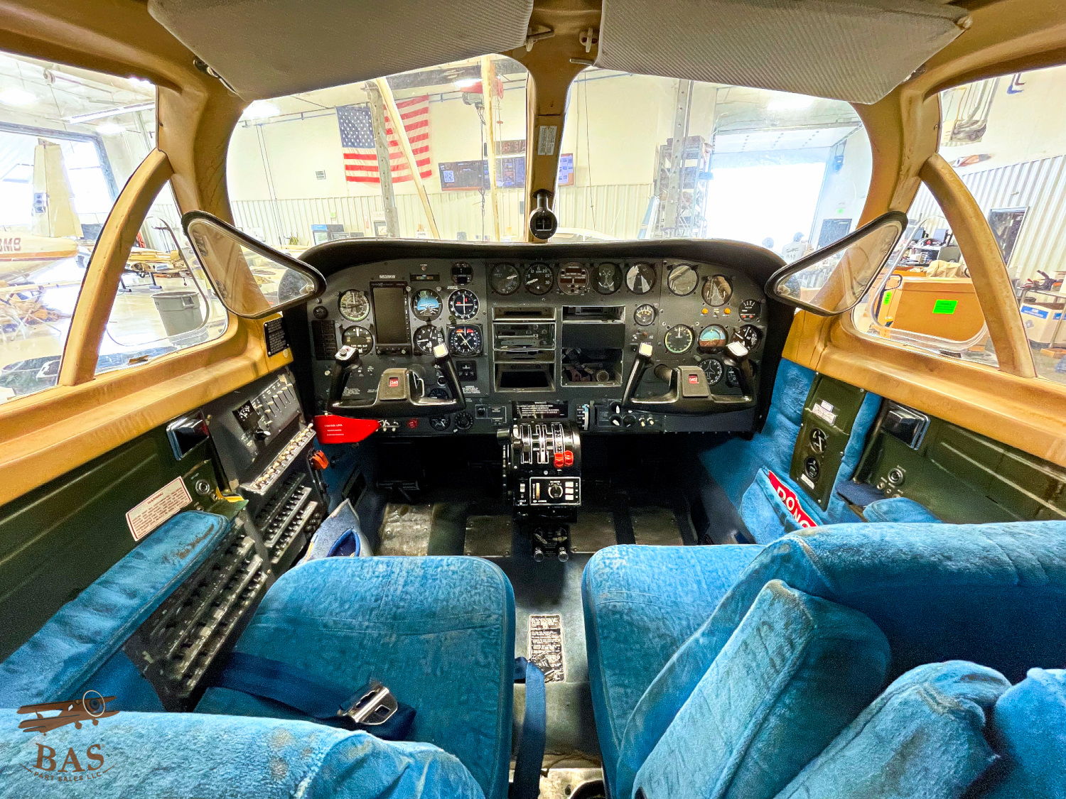 Cockpit interior of an aircraft with blue seats and control panel.