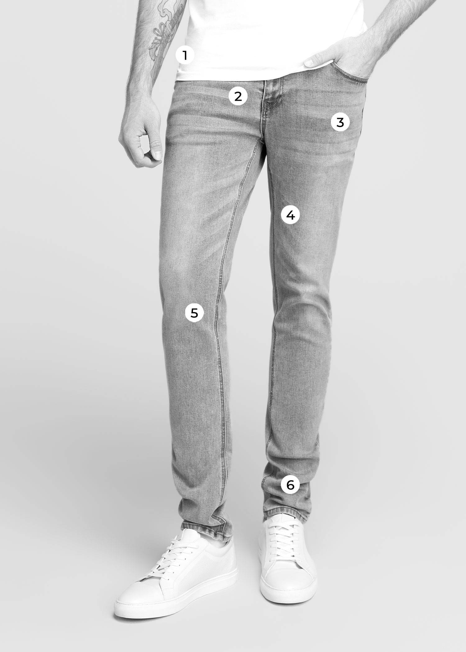 Tall man wearing light wash jeans with his hand in his pocket.