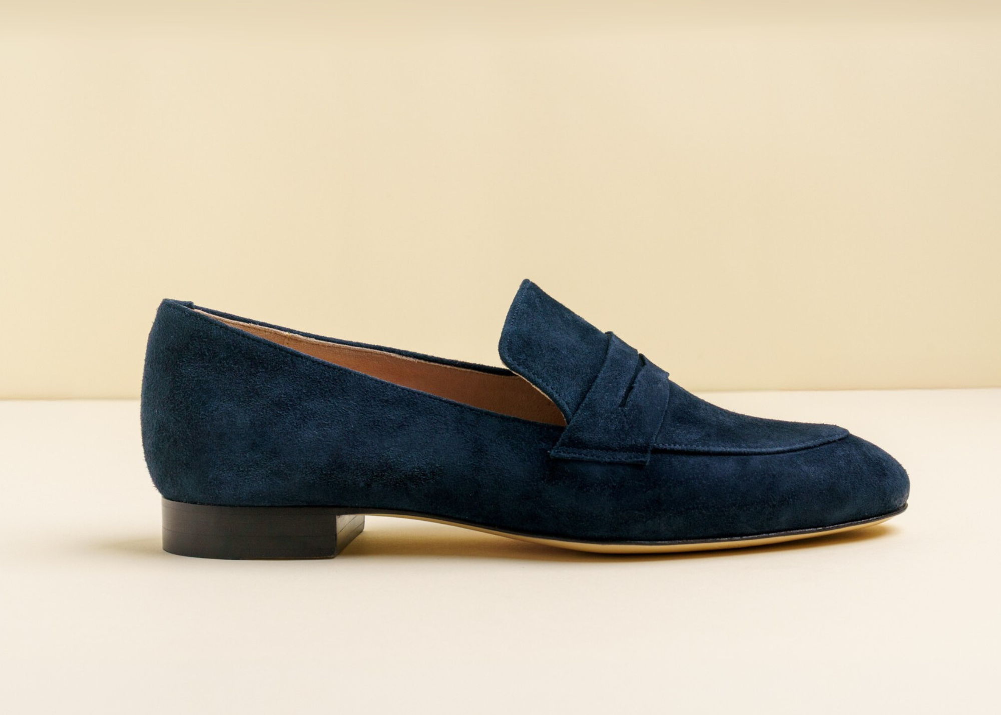 Navy suede loafers on a neutral background.