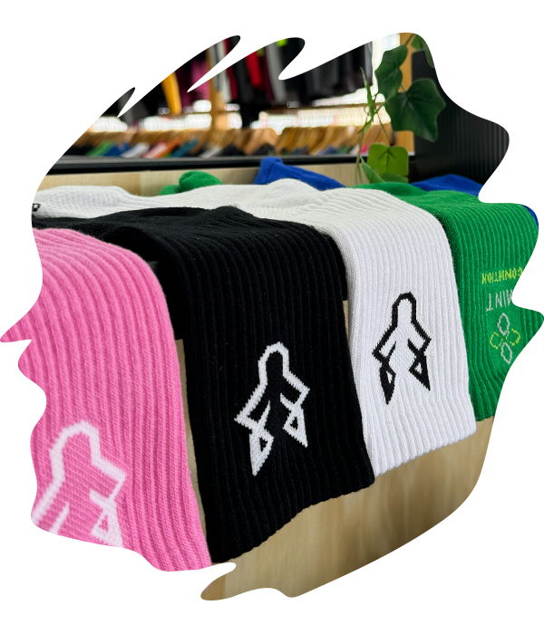 Ribbed black, pink, green, and white woven socks with woven logo designs displayed on a retail shelf