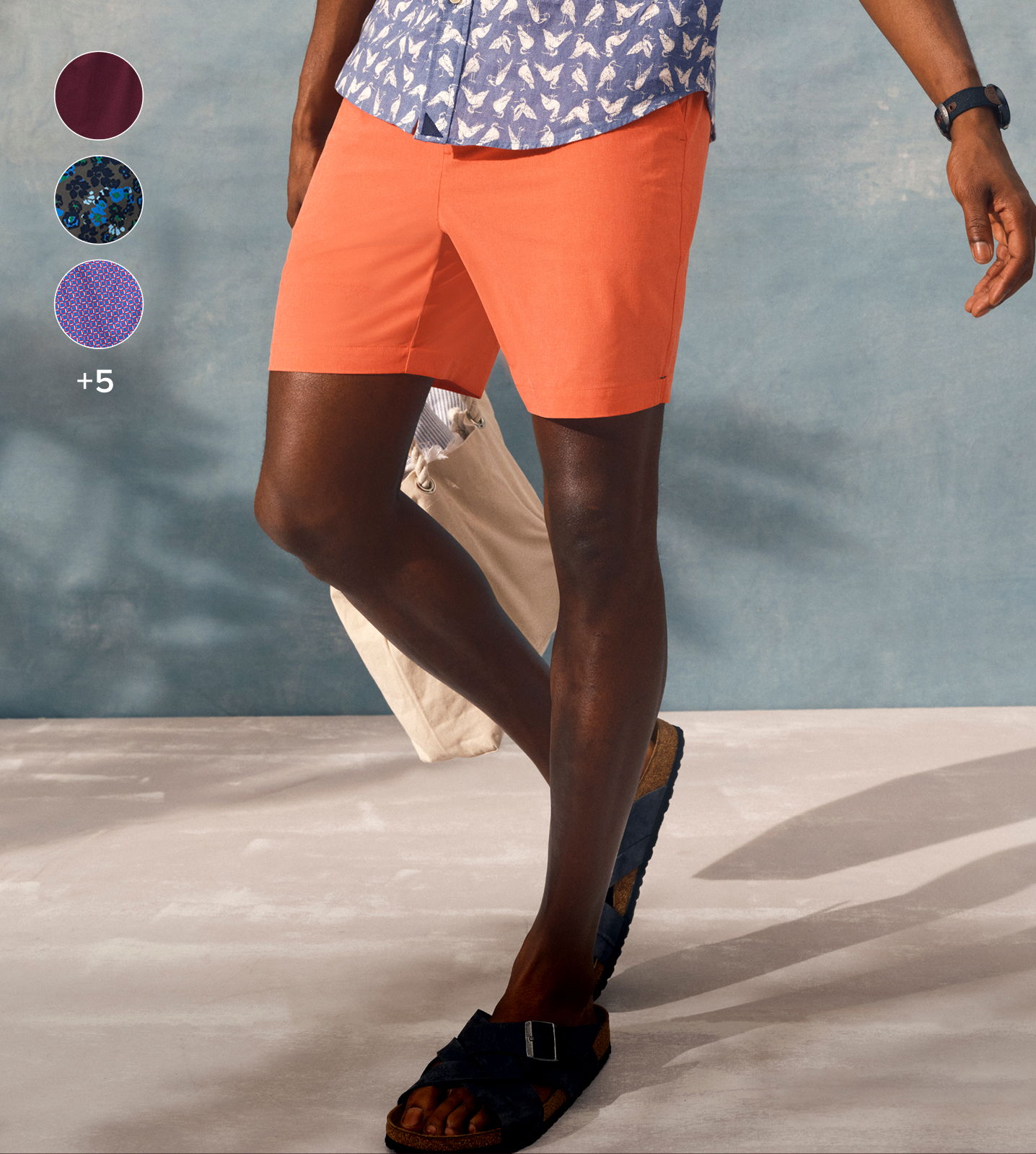 Person wearing orange shorts and a patterned shirt, standing on a light surface.