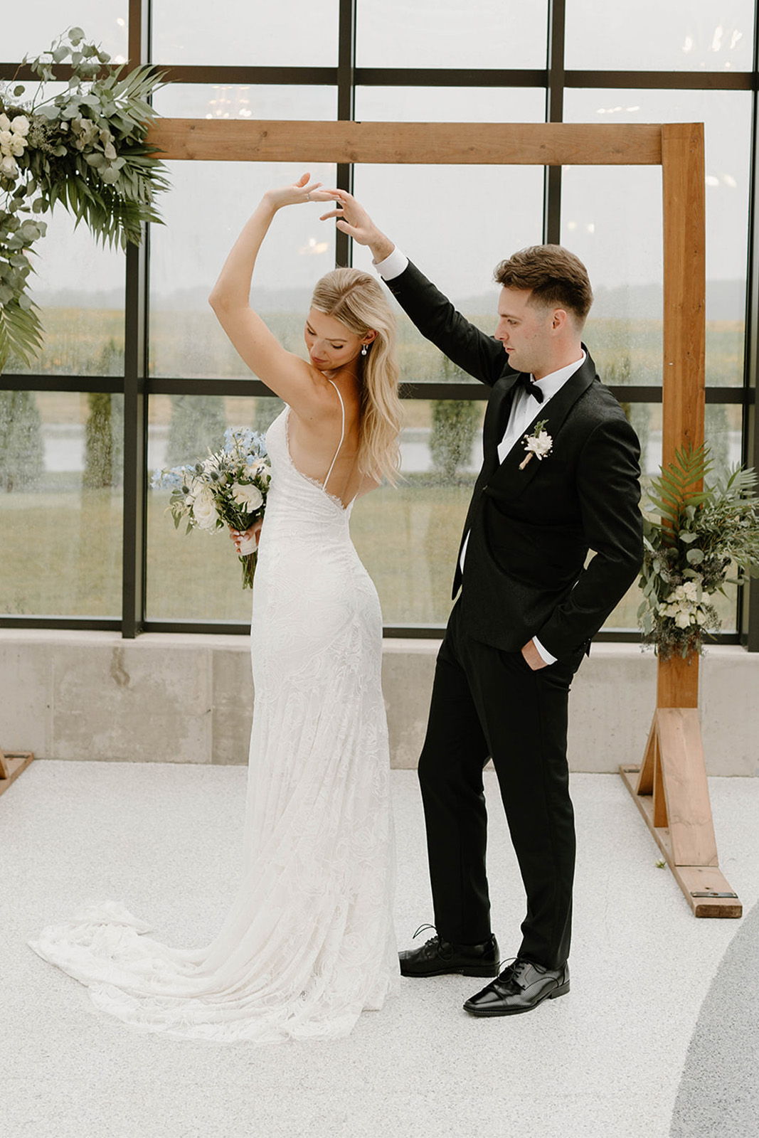 Couple dancing at a wedding under a floral archway.