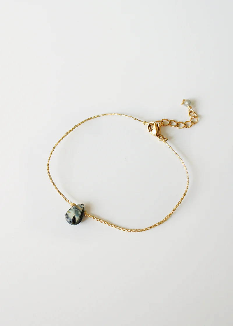 A simple gold bracelet with a labradorite faceted teardrop charm