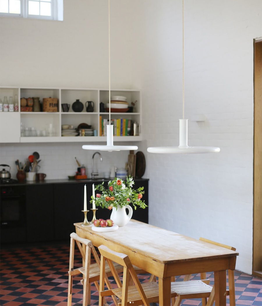 Modern kitchen with wooden dining table and pendant lights.