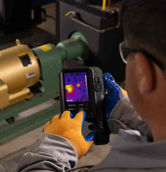Technician using a FLIR iXX Series thermal camera to inspect an industrial motor and pump system | GoThermal