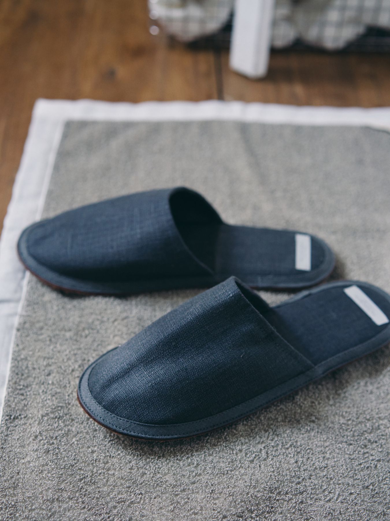 A pair of black slippers on a textured rug.