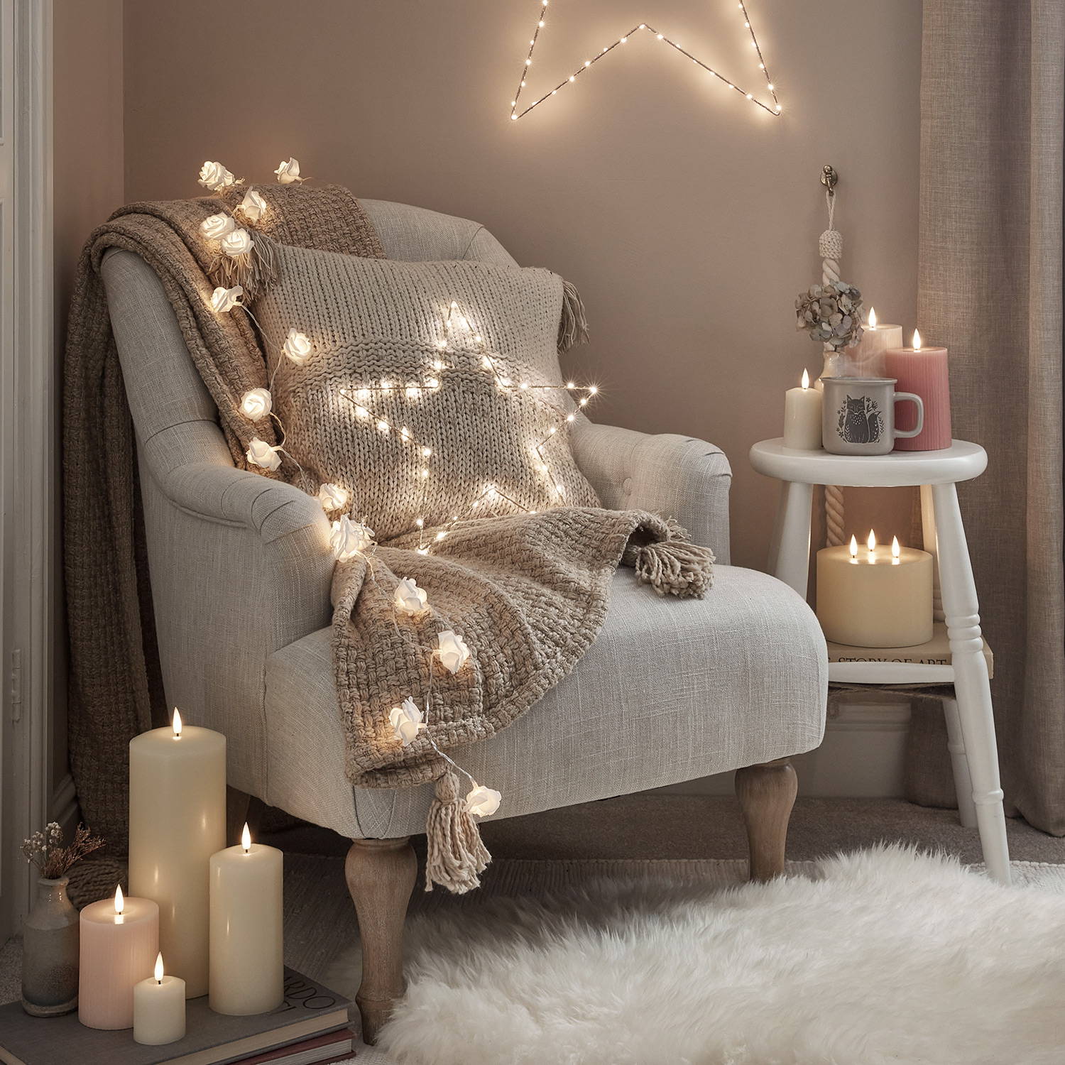 A cosy armchair setting with fairy lights, LED candles, osby stars and cushions and blankets.