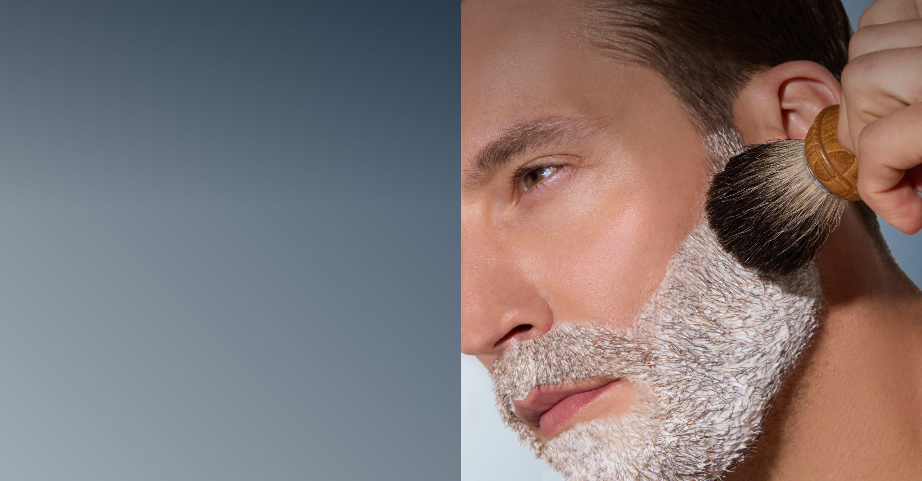Man applying shaving cream with a brush, half of face visible.