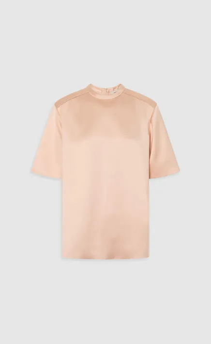 Short-sleeved, light pink top on a gray background.