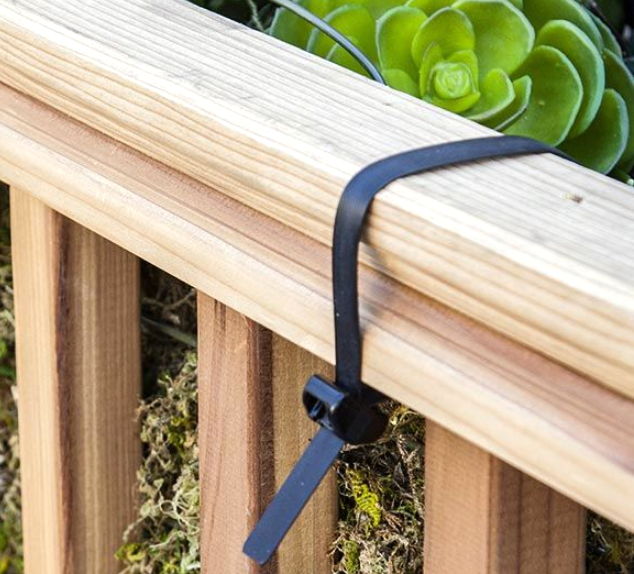 A black zip tie securing a wooden railing.