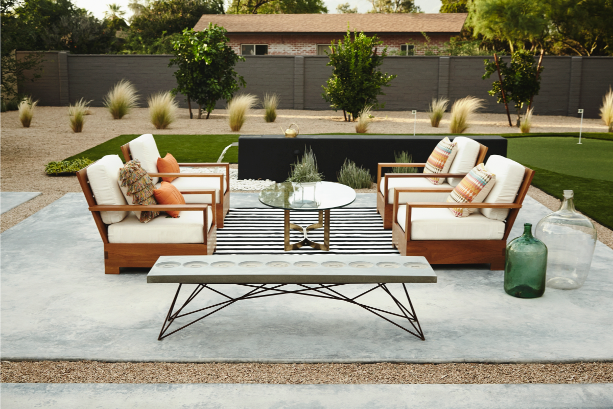 An outdoor sitting area featuring the Orson lightweight concrete coffee table with metal frame and distinct circle pattern on surface.
