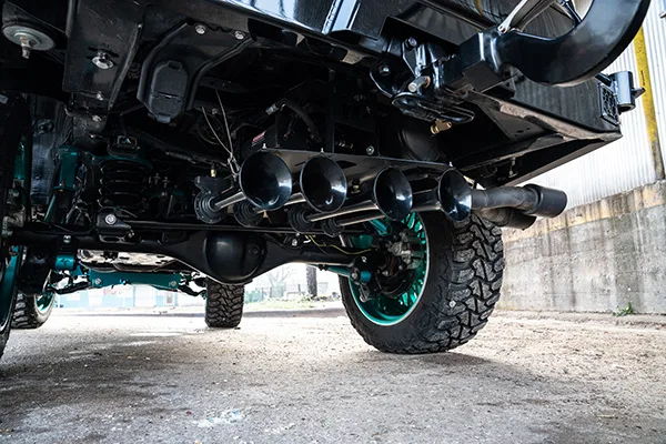 Low-angle four black train horns rear axle teal suspension off-road tires undercarriage Kealoha's 244K Spare Tire Delete install gallery photo 2