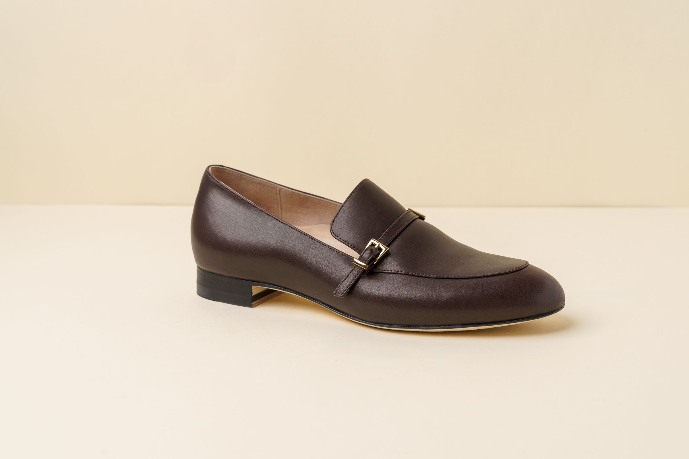 Brown leather loafer shoe on a light background.