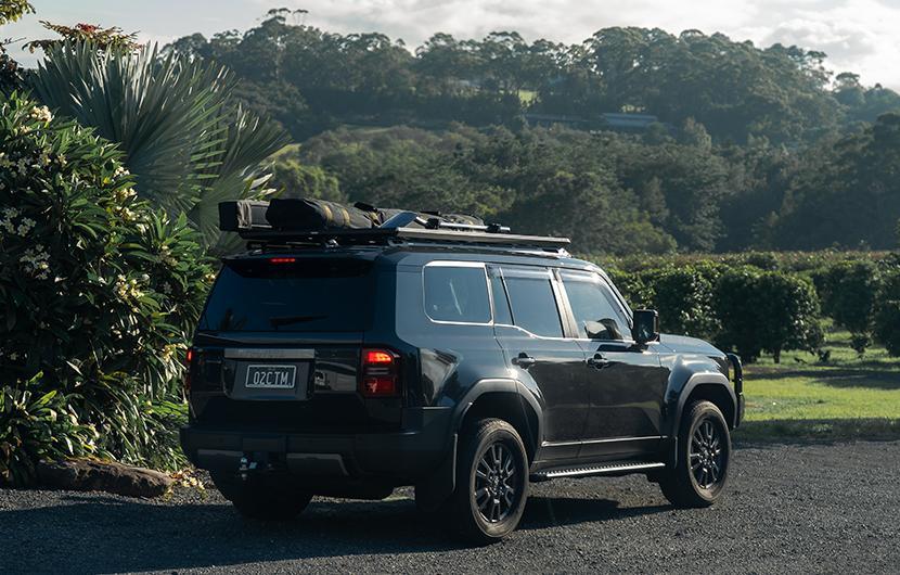 A Toyota Landcruiser with Yakima LockNLoad Platform and Ruggedline in front of green trees