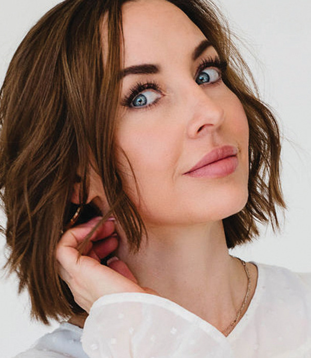 A woman with short hair poses with a thoughtful expression.