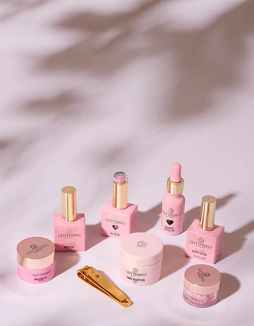 Collection of pink cosmetic products arranged on a soft surface.