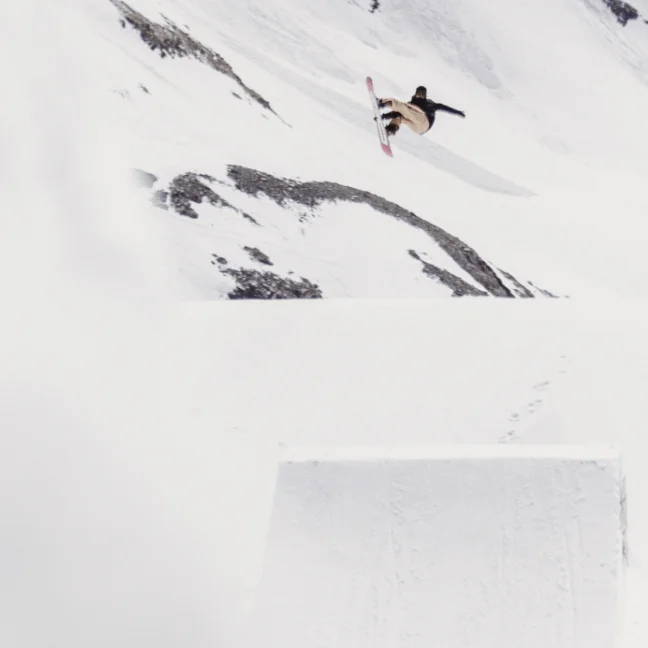 Person snowboarding in the mountains and performing a jump