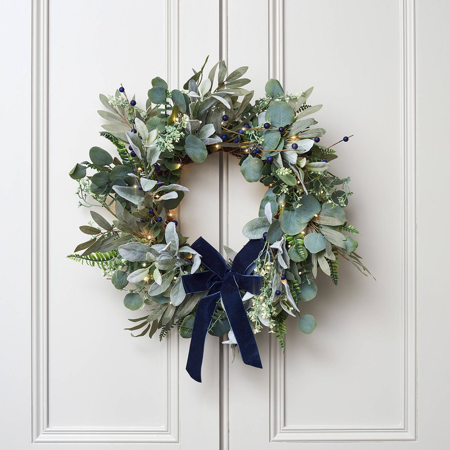 Blue berry Christmas wreath with micro lights hanging on a door
