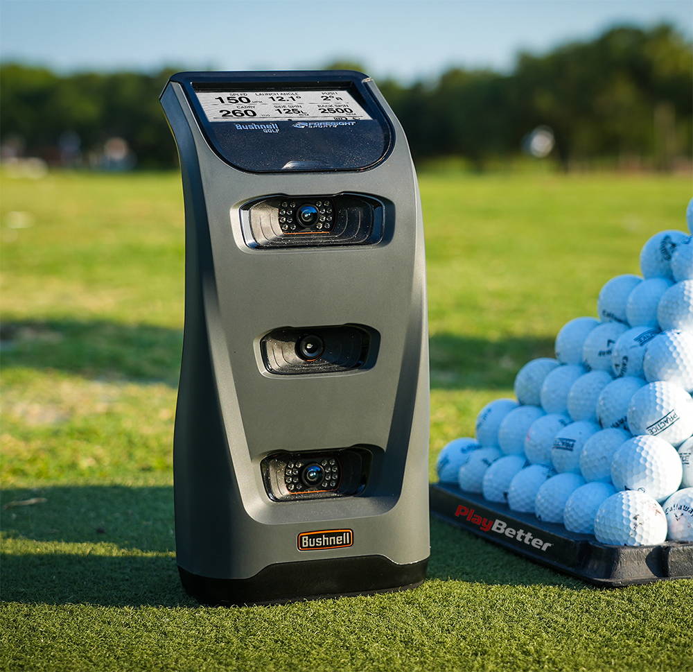 The Bushnell Launch Pro at the golf range next to a pyramid of golf balls