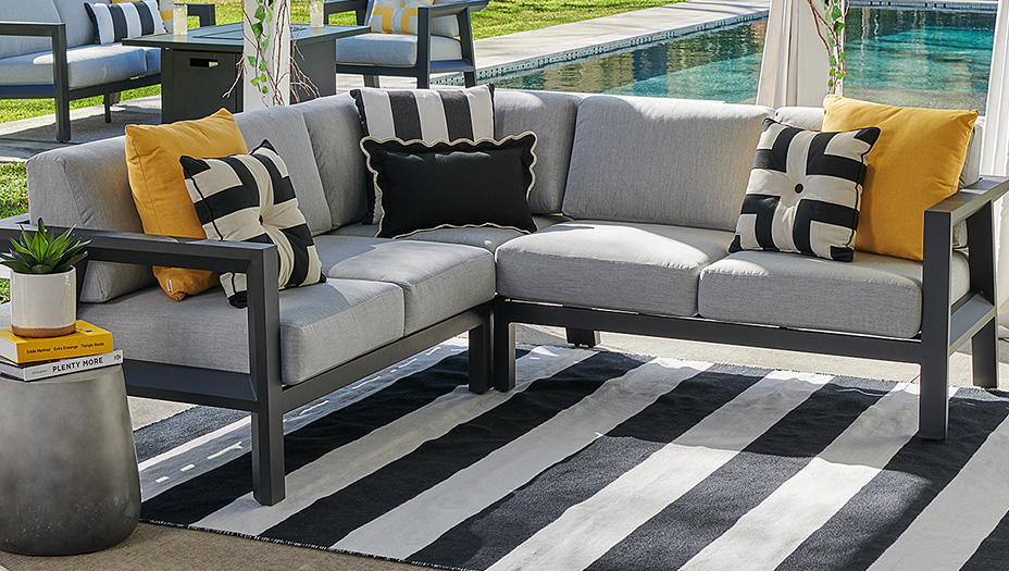 Outdoor seating area with gray sectional sofa and striped rug.