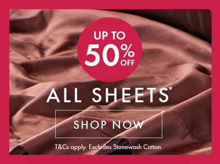 Up to 50% Off All Sheets* promotional text with Shop Now button and T&C's against a chocolate bed sheet background