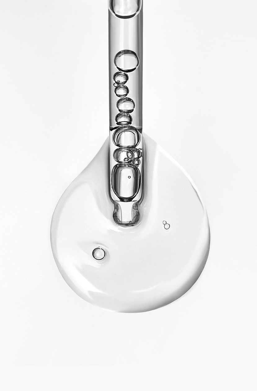 A clear liquid drop with bubbles against a white background.