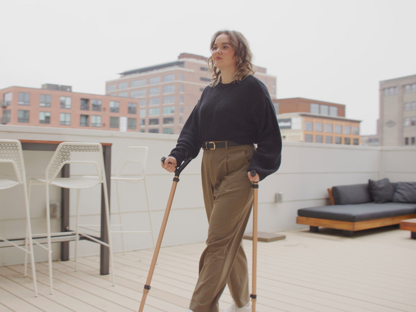 Young woman walking outdoors using pair of Y-Cane in rose gold finish, demonstrating upright posture