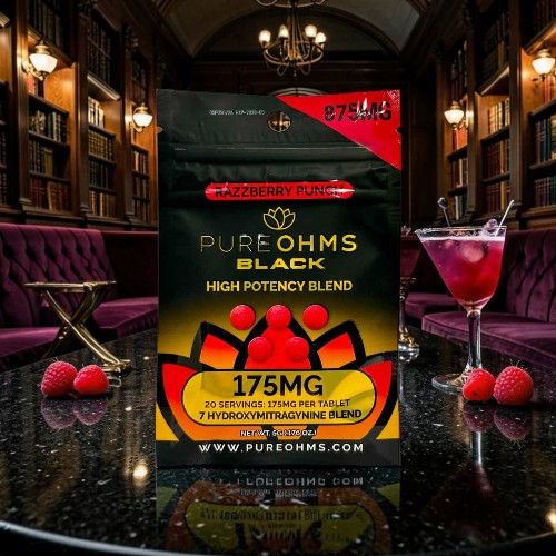 Package of Pure Ohms Black on a table with a cocktail and raspberries.