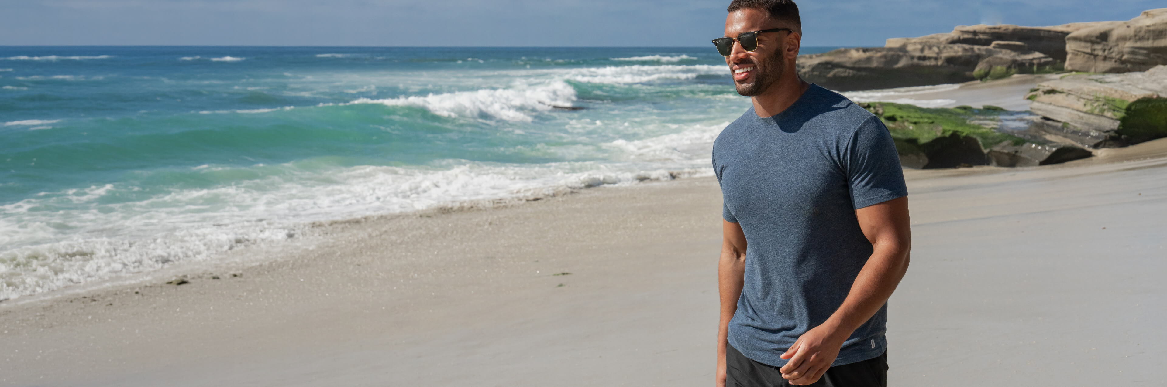 a man walking on a beach wearing a cariloha t-shirt