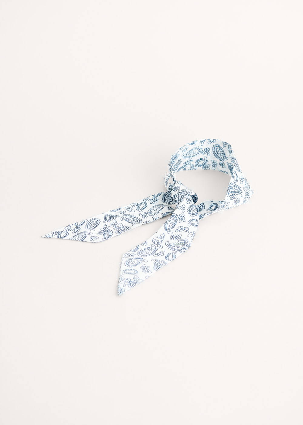 A white satin neckercheif with blue paisley pattern