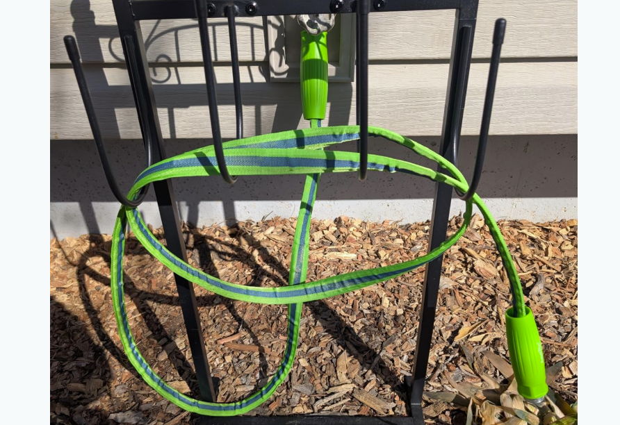 A green hose coiled on a black stand outside.