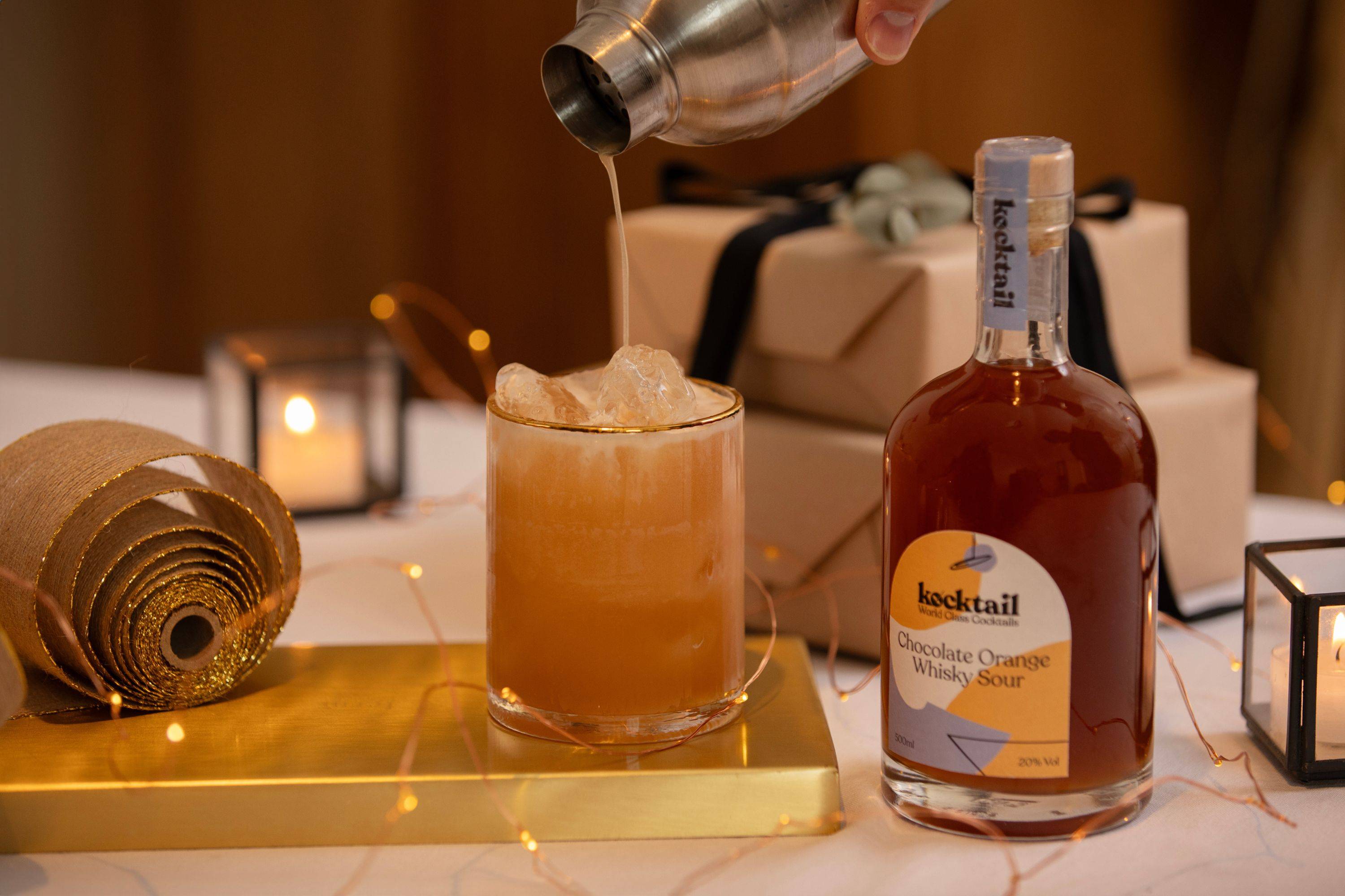 Chocolate orange whisky sour cocktail being poured into a glass on dining table 