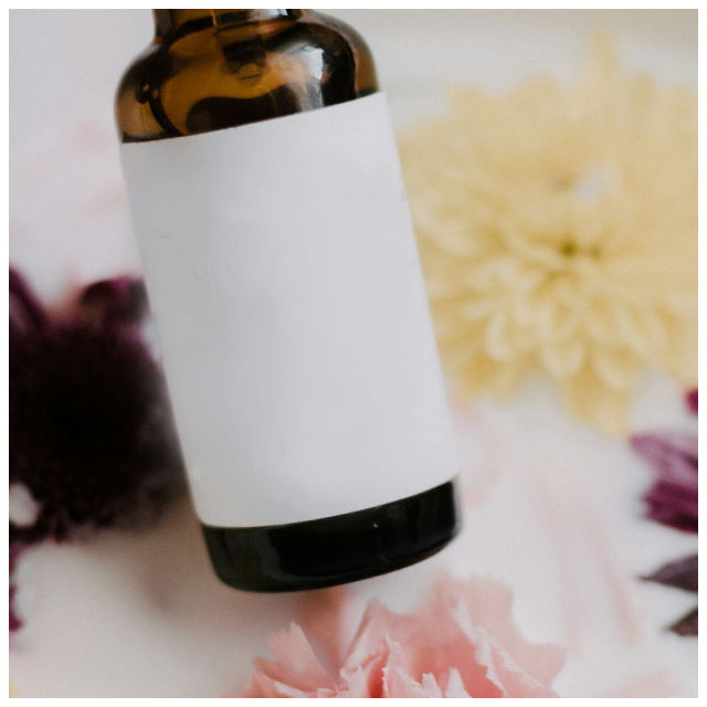 A bottle with a white label, laying on a table with several flower blooms in the background