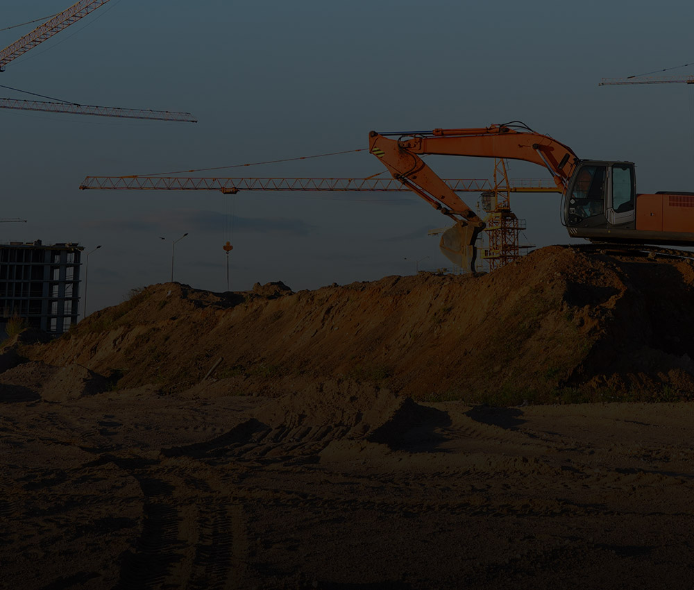 Construction site with cranes, excavator, and building in progress, representing security and monitoring solutions for the construction industry