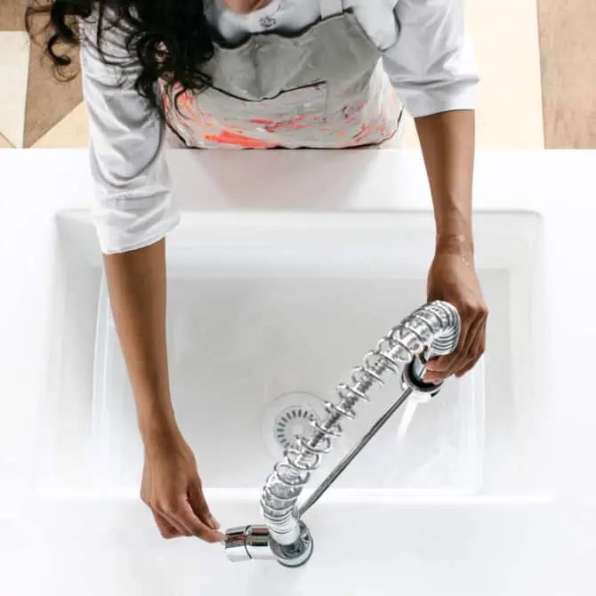 Person adjusting a modern kitchen faucet over a white sink.