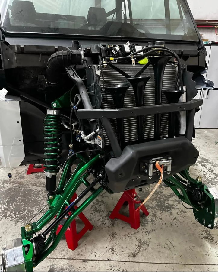 Front end on jack stands Conductor's Special train horns metallic green A-arms winch brush guard shop install Rich's Can-Am Defender 244K gallery photo 3