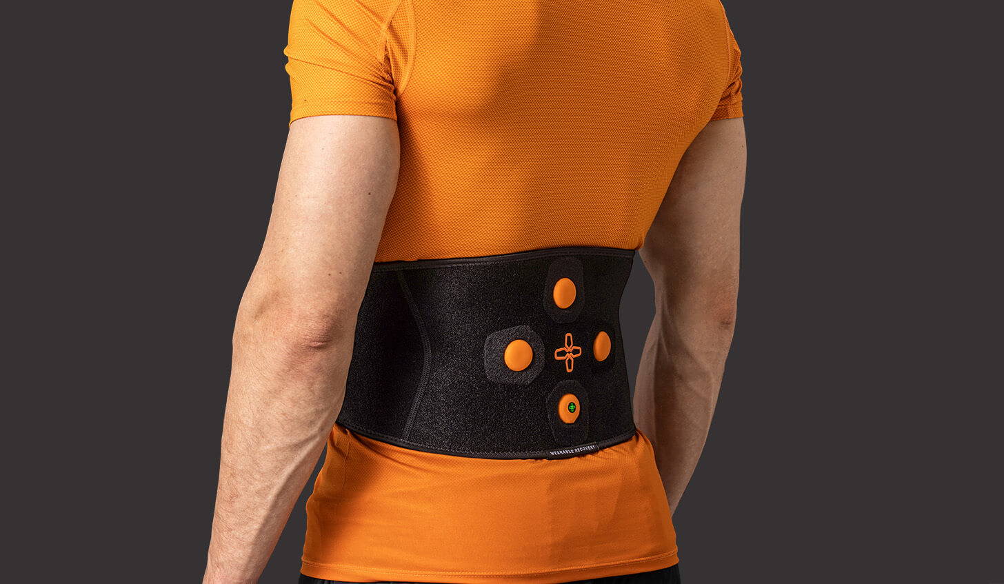 Myovolt vibration therapy device for lower back muscle recovery treatment worn by a male athlete.