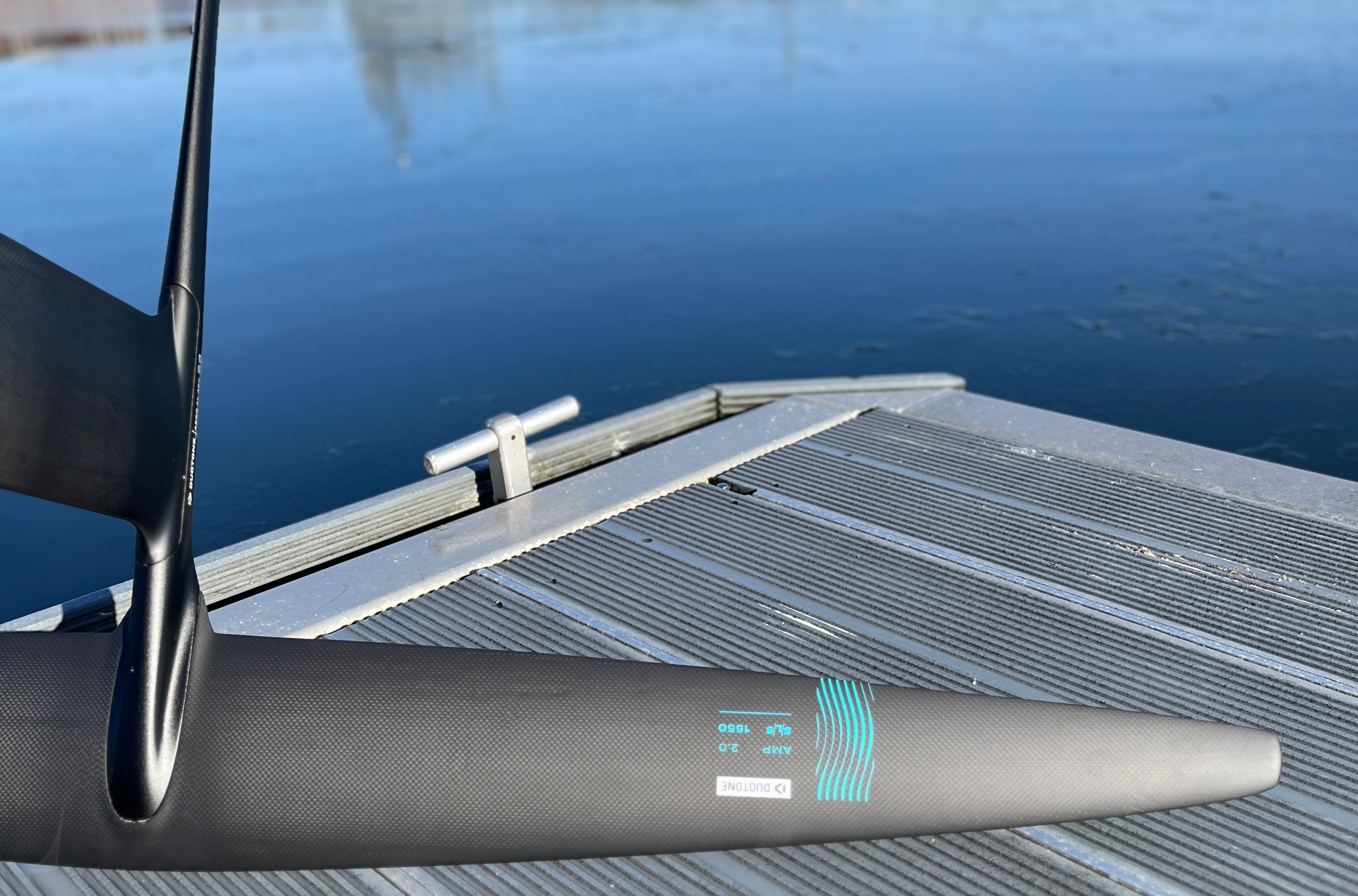 Close-up of a boat's rudder on a dock by calm water.