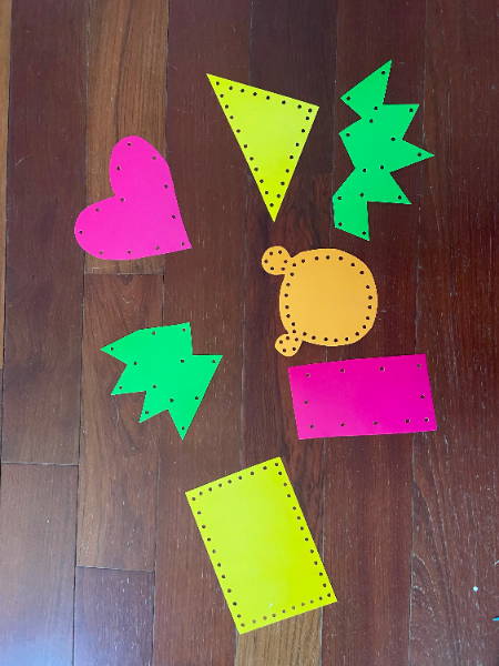 holes punched into various shapes of posterboard for lacing cards