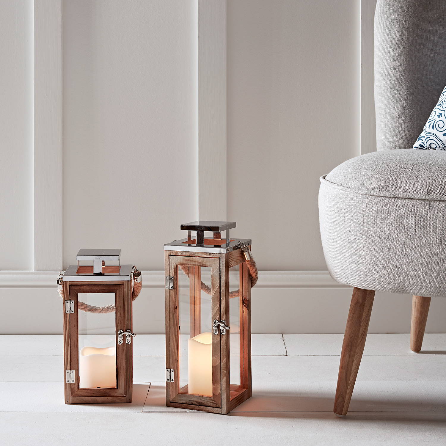 2 lanterns and candles on the floor of a living room.