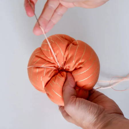 Making pumpkin sections by hand sewing through the pumpkin with embroidery floss