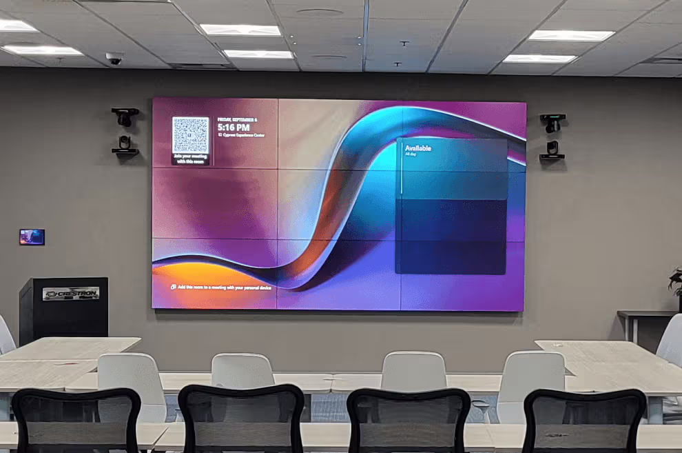 Conference room with a large display screen and seating arrangement.