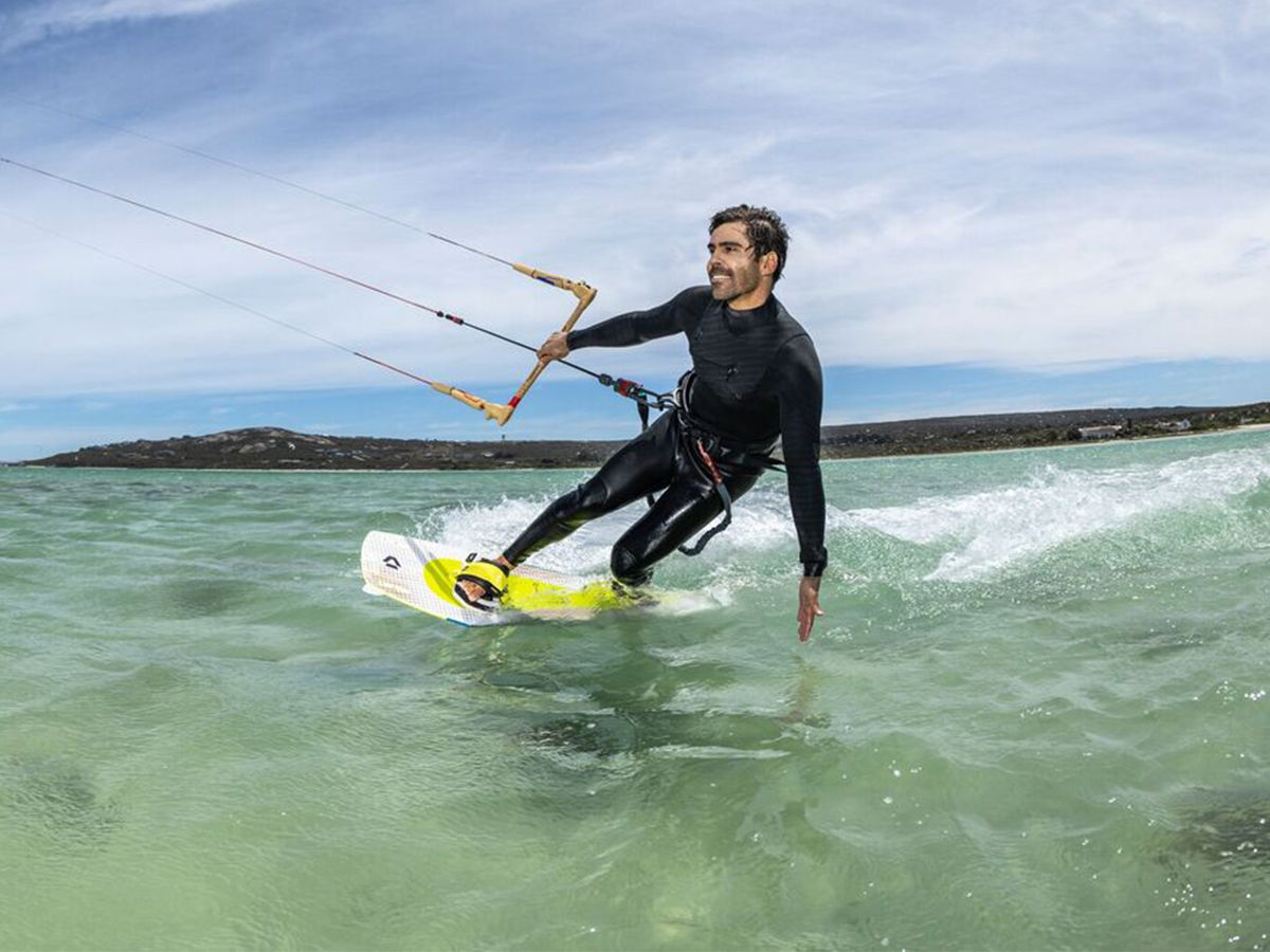 Person kitesurfing on water with a clear sky in the background.