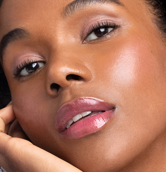 Close-up of a woman with glowing skin and glossy lips.