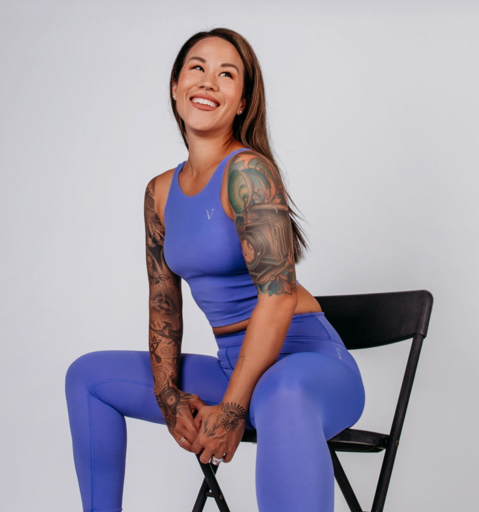 Smiling person in purple athletic wear sitting on a chair.